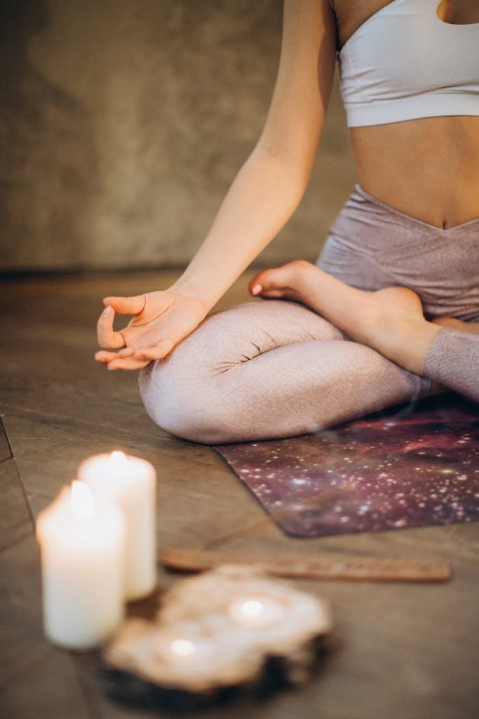 meditating-with-candles-and-incense-3822621 A woman practicing yoga indoors in lotus pose with candles creating a calming atmosphere.